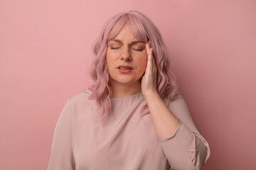 Handsome pink hair 30s woman standing with hand on head for pain in head because stress over...