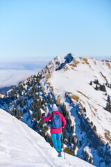 nice senior woman snowshoeing on the Nagelfluh mountain chain above a sea of fog over Bregenz Wald...
