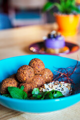 Falafel balls with hummus served in a blue plate on a wooden table. Vegan and vegetarian food