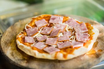 The chef is preparing the pizza with ham before putting it in the oven. use traditional firewood