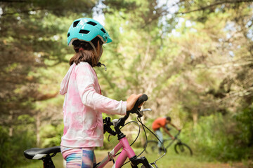 happy child girl riding a bike on natural background, forest or park. healthy lifestyle, family day out