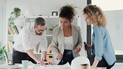 Video of smart architects working with plans while talking of their new design business in the office.