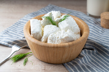 Traditional homemade salted cottage cheese cheese in a wooden bowl - obrazy, fototapety, plakaty