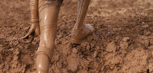 Mud race runner detail of the legs, muddy running shoes a run in the mud