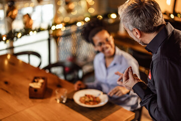 Gray-haired caucasian waiter, making sure his customer is satisfied.