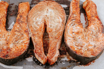 Red fried fish steaks. Baked salmon pieces. Juicy appetizing salmon lies on baking sheet. Healthy food concept