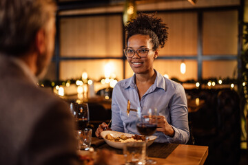 Relaxed African-American woman with glasses, holding a piece of food on her fork.