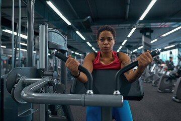 Fototapeta na wymiar Girl doing exercise on training apparatus in gym