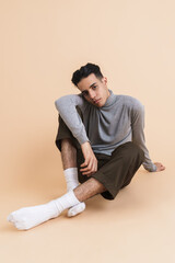 Young middle eastern man looking at camera while sitting on floor