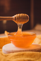 Honey dripping from honey dipper in bowl. Close-up. Healthy organic Thick honey dipping from the...