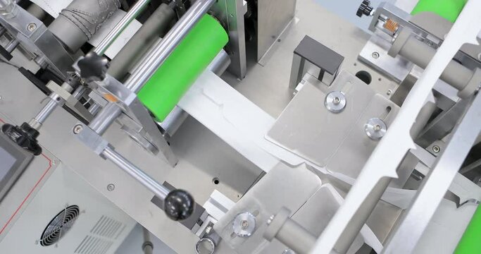 Production of disposable medical clothing for protection against the virus. Medical mask on conveyor belt in the workshop of factory for production of medical clothing. Manufacture of medical masks.