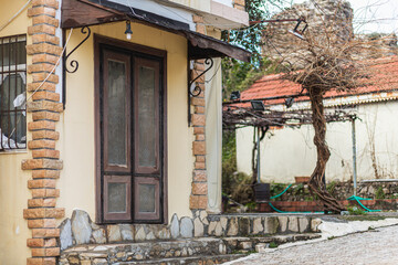 Close-up of a porch with a brown door in an old stone mansion house