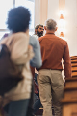 African american student looking at camera near blurred friends and teacher in university