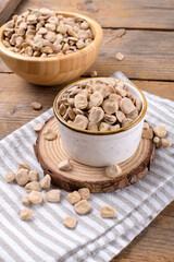 Cicerchia or indian pea on a ceramic bowl with napkin on natural wooden background, close up. Legumes known as Lathyrus Sativus, Chickling Vetch, Blue Sweet Pea made in Puglia, close up