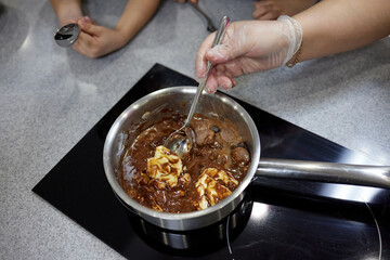 Woman melting chocolate in a pan and mix it with butter, close-up. Cooking at home, homemade sweet...