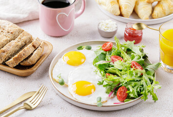 Healthy breakfast with scrambled fried eggs and fresh green salad, fresh bread, croissants, orange juice and coffee. Selective focuse.