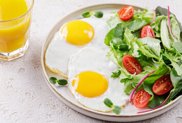 Healthy breakfast with scrambled fried eggs and fresh green salad with organic microgreens and cherry tomatoes. Egg breakfast. Selective focuse.