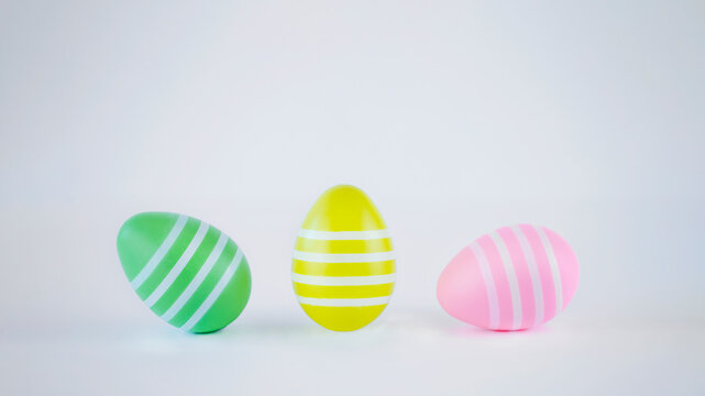 Green, yellow and pink easter eggs on white background. Easter image with copy space