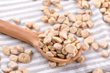Dry Cicerchia or indian pea on a wooden spoon on a cotton napkin, close up, food gluten free. Legumes known as Lathyrus Sativus, Chickling Vetch, Blue Sweet Pea made in Puglia, top view