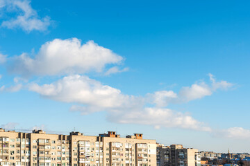 Fototapeta na wymiar City houses on a background of clouds and blue sky