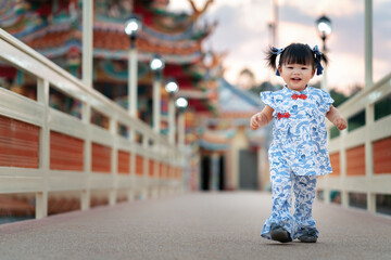 Asia Chinese baby girl in chinese tradition cloth walk in temple use as concept of Chinese New Year and baby. Cute Asian  baby girl sit, stand, play and relax at outdoor.
