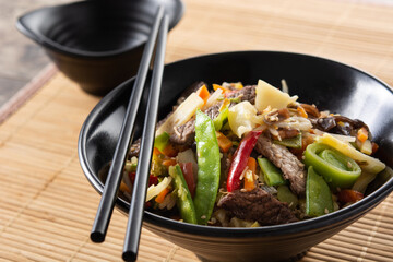 Beef, vegetables and sesame seeds in black bowl