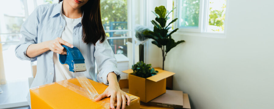 close up hand of woman packing cardboard box indoors