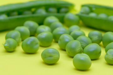 Organic green peas, freshly picked and peeled from the pod, on the yellow background. Concept of healthy eating, from Dalmatia