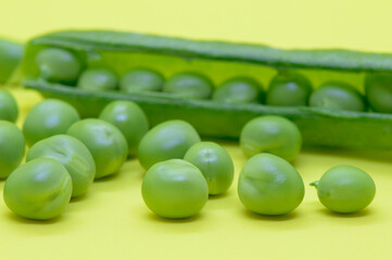 Organic green peas, freshly picked and peeled from the pod, on the yellow background. Concept of healthy eating, from Dalmatia