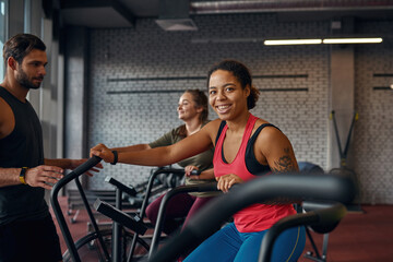 Trainer looking at girl doing exercise on orbitrek