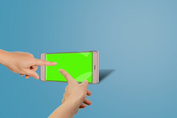 Modern smartphone on stand with green chroma key screen and female hands pointing on it