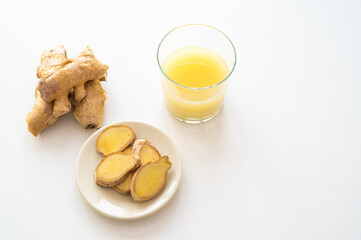 Obraz na płótnie Canvas Ginger root, with pieces of ginger next to it and a glass of ginger juice. 