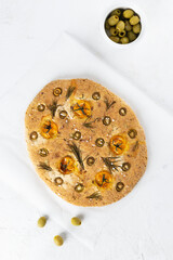 Vegan focaccia with olives, tomatoes, rosemary and spices on a table. Sugar, gluten and lactose free, vegan.Vertical orientation, top view.