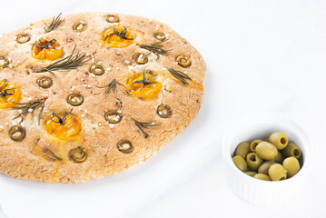 Vegan focaccia with olives, tomatoes, rosemary and spices on the table. Sugar, gluten and lactose free.