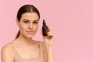 Fototapeta premium A beautiful young woman moisturizes her skin with a serum. Caring for the skin. Essential Oil For Anti-Aging Therapy