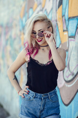 Fototapeta premium Portrait of young woman with piercings and tattoos against graffiti wall.