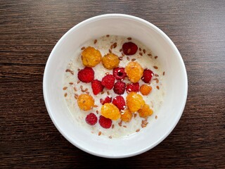 great photo. milk oatmeal with yellow and red flax and flax and sesame seeds in a deep white bowl. healthy wholesome food. vitamins. eco.