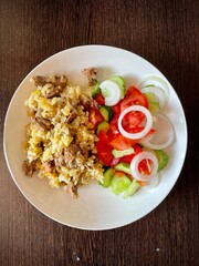 large vertical photo. pilaf and fresh vegetable salad on a white plate. top view close-up. homemade food.