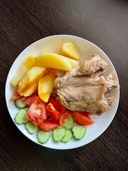 large vertical photo. fried rabbit meat with potatoes and fresh vegetables on a white plate. Healthy food. ECO. Home serving.