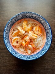 large vertical photo. funchose with shrimps in a colored deep plate on a brown background. dish with seafood. Healthy food. ECO. Home serving.
