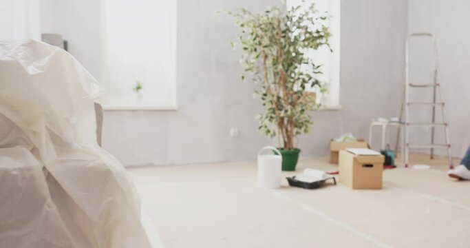 View of an apartment in its raw state during renovation painting walls two people in love sitting on floor drinking coffee and browsing in tablet inspirations of rooms, furniture, decorations