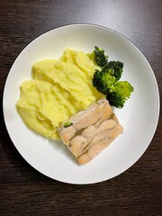 large vertical photo. homemade food. mashed potatoes with fried pink salmon and broccoli on a white round plate. kind of serhu. healthy food. diet food. eco.