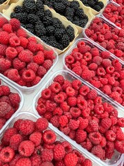 large vertical photo. raspberries and blackberries in plastic containers. containers with berries standing diagonally. photo above. healthy natural berries. eco.