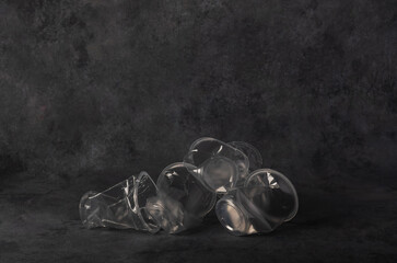 A pile of disposable crumpled plastic cups for disposal and recycling on a gray background.