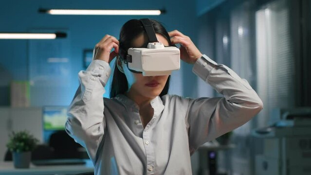 Asian businesswoman wearing virtual reality headset in modern office