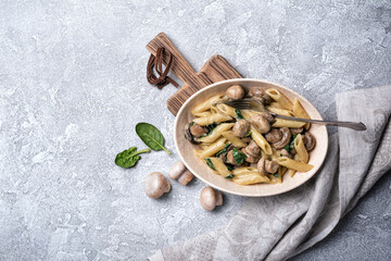 Fototapeta na wymiar Bowl of pasta and mushrooms in cream sauce with spinach