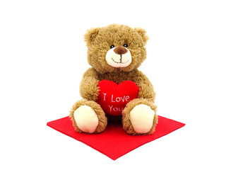 Brown teddy bear holding red heart with text 'I love you', isolated on white background.