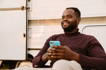 Black man using mobile phone during journey on trailer