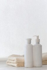 Set of white cosmetic bottles mockup with a towel and a natural soap on a white table. Hygiene and healthy life concept. Close up, selective focus
