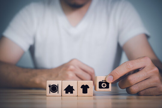The investor's hand placed a wooden cube with word Work on wooden table. concept work from home, Planning to buy property concept ,food Clothing, housing, medicine, four basic human needs concept.